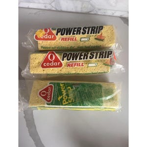 Puede incluir: Tres paquetes de recambios O-Cedar Power Strip. Cada paquete contiene una esponja amarilla con el texto "Power Strip Refill". El embalaje indica que elimina la suciedad persistente y las marcas de tacón.