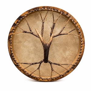May include: A circular frame drum featuring a tan drumhead made of stretched hide. A central wooden branch structure is secured to the drumhead with thin, dark brown cordage that radiates outward to the wooden rim, which is wrapped in braided leather.