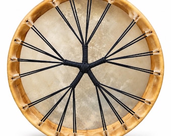 May include: A circular frame drum featuring a light tan animal hide head stretched over a smooth wooden hoop. The drum head is secured by a network of black cord lacing that radiates from a central knotted point to the outer wooden frame.