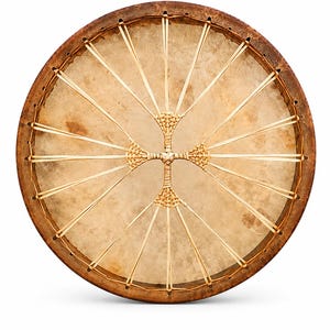 Puede incluir: Un tambor de marco circular con un parche de piel animal en tono bronceado natural estirado sobre un aro de madera marrón oscuro. El parche está asegurado por un complejo sistema de cordones claros que forman una cruz en el centro.