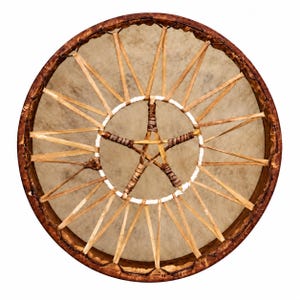 May include: A circular frame drum with a light tan rawhide head stretched over a dark brown wooden rim. The drum features a central five-pointed star design created with wrapped leather lacing, connected to the outer rim by radiating leather strips.