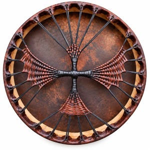 Pode incluir: Um tambor de moldura circular com uma pele de cor castanho-escura manchada. O aro é revestido a couro castanho-escuro e a parte de trás apresenta um sistema complexo de atacadores pretos e tiras entrançadas formando uma cruz central.