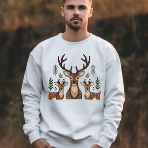 Peut inclure: Sweat-shirt blanc orné d'une broderie représentant une famille de cerfs. Le motif comprend un grand cerf avec des bois, deux petits cerfs et des feuilles vertes. Un vêtement de style décontracté.