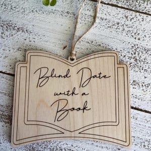 May include: Wooden book-shaped ornament with the text "Blind Date with a Book" in a cursive font.