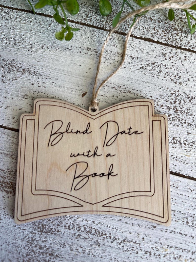May include: Wooden book-shaped ornament with the text "Blind Date with a Book" in a cursive font.