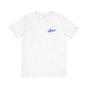 Peut inclure: T-shirt blanc à col rond et manches courtes. Le t-shirt porte le texte bleu "LYVON" sur le devant. Le t-shirt est fait d'une matière douce et légère.