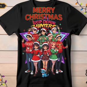Puede incluir: Camiseta negra con un gráfico navideño. El diseño presenta un grupo de personajes de dibujos animados con gorros de Papá Noel y atuendos festivos, con el texto "MERRY CHRISTMAS KPOP DEMON HUNTERS". También se incluye un gato de dibujos animados azul.