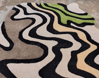 May include: A modern area rug with a unique, abstract design. The rug features flowing, wavy patterns in black, white, beige, tan, and green. The rug's design creates a visually interesting and contemporary aesthetic, suitable for various interior styles.