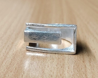 Anillo geométrico llamativo de plata de ley, banda ancha de estilo brutalista arquitectónico.