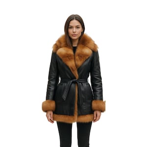 Puede incluir: Un abrigo de cuero negro con cuello, puños y ribete de piel marrón. El abrigo tiene cinturón en la cintura y un diseño clásico. La modelo lleva pantalones negros. Una prenda de abrigo elegante.