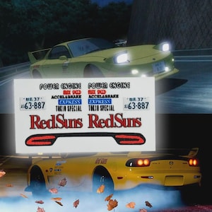 May include: A yellow sports car with pop-up headlights and a rear spoiler is shown in motion. A sticker with the text "POWER ENGINE", "RedSuns", and other Japanese text is in front of the car. The car is on a road with a blurred background.