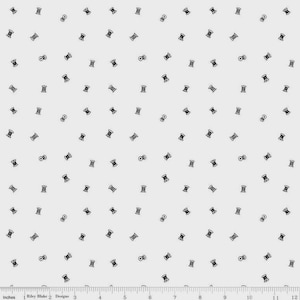 May include: A light gray fabric with a repeating pattern of small black spools of thread and bobbins. The spools and bobbins are scattered across the surface. The fabric has a ruler along the bottom edge with the text "Riley Blake Designs".