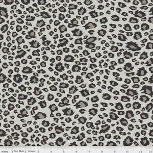 May include: A fabric with a leopard print pattern. The design features dark brown and gray spots on a light gray background. The pattern is dense and covers the entire surface, creating a textured appearance. The fabric is measured in inches.