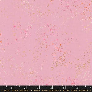May include: Pink fabric with a speckled design. The fabric features a light pink background with scattered specks of gold, white, orange, and pink. The bottom of the fabric has a ruler with the text "RUBY STAR SOCIETY".