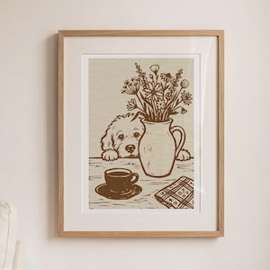 May include: A framed print featuring a dog peeking over a table with a vase of flowers, a cup of coffee, and a patterned napkin. The artwork is in shades of brown and beige, creating a warm, inviting scene. The print is displayed in a light wood frame.