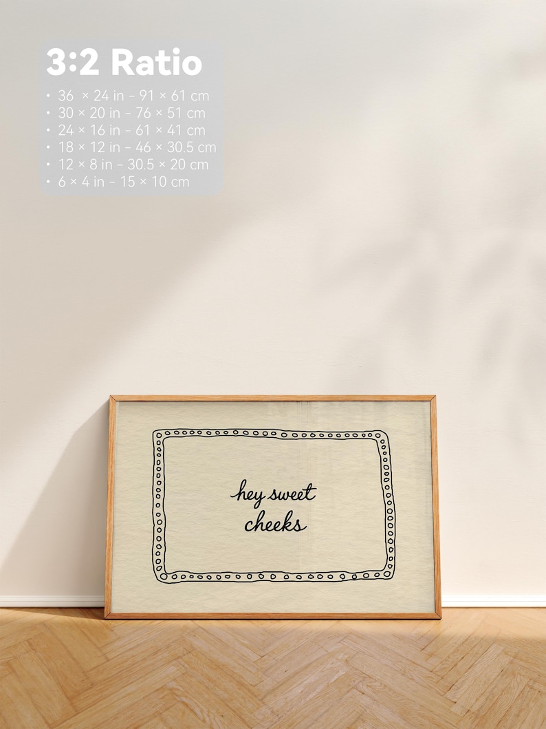 May include: A framed print with the text "hey sweet cheeks" in a handwritten style. The print is in a wooden frame and has a decorative border. The image also includes size options in inches and centimeters.