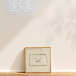 May include: A framed print with the text "hey sweet cheeks" in a decorative frame. The frame is made of light-colored wood. The print is leaning against a wall on a wooden floor. The image also includes size conversions: 20 x 20 in to 51 x 51 cm, 16 x 16 in to 41 x 41 cm, etc.