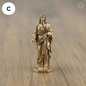 Puede incluir: Una peque&ntilde;a estatua de bronce de Jesucristo. La figura, con pelo largo y barba, viste t&uacute;nicas drapeadas. Jes&uacute;s sostiene un globo terr&aacute;queo en una mano y gesticula con la otra. La estatua tiene un dise&ntilde;o detallado y se apoya en una base hexagonal.