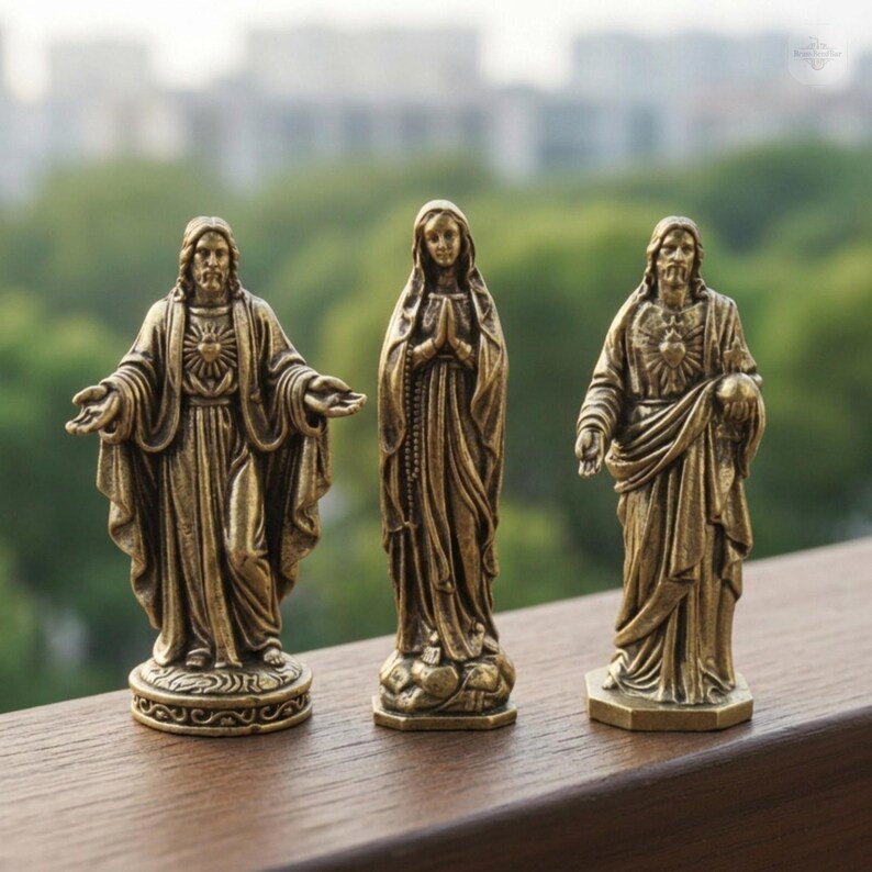Puede incluir: Tres estatuas religiosas de bronce. Dos estatuas representan a Jes&uacute;s con los brazos abiertos y un emblema de coraz&oacute;n. La tercera estatua es de Mar&iacute;a con las manos juntas en oraci&oacute;n. Todas las estatuas tienen t&uacute;nicas detalladas y bases decorativas.