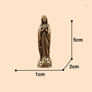 Puede incluir: Peque&ntilde;a estatua de bronce de la Virgen Mar&iacute;a, de pie con las manos juntas en oraci&oacute;n. La estatua mide aproximadamente 2 cm de ancho, 1 cm de profundidad y 5 cm de alto. La figura est&aacute; detallada con t&uacute;nicas fluidas y una expresi&oacute;n serena.