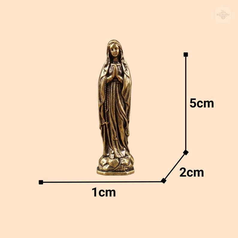 Puede incluir: Peque&ntilde;a estatua de bronce de la Virgen Mar&iacute;a, de pie con las manos juntas en oraci&oacute;n. La estatua mide aproximadamente 2 cm de ancho, 1 cm de profundidad y 5 cm de alto. La figura est&aacute; detallada con t&uacute;nicas fluidas y una expresi&oacute;n serena.