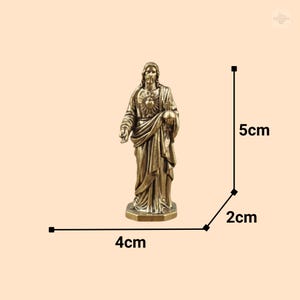 Puede incluir: Una estatua de color bronce de Jesucristo, de pie sobre una base hexagonal. La estatua mide 5 cm de alto, 4 cm de ancho y 2 cm de profundidad. Jes&uacute;s est&aacute; representado con pelo largo y barba, vistiendo t&uacute;nicas drapeadas.