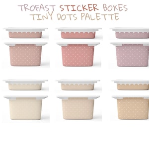 Puede incluir: Nueve pequeñas cajas de almacenamiento rectangulares con tapas blancas y bordes festoneados. Las cajas son de varios tonos de rosa, beige y melocotón, algunas con un estampado de lunares. El texto "TROFAST STICKER BOXES TINY DOTS PALETTE" está en la parte superior.