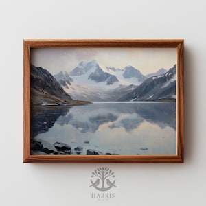 May include: A framed landscape painting depicts a serene mountain lake scene. Snow-capped mountains are reflected in the calm water. The artwork is encased in a warm, brown wooden frame, creating a classic aesthetic.