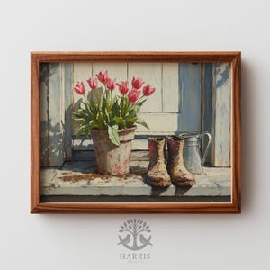 May include: A framed print of a still life featuring a potted plant with pink tulips, a pair of worn boots, and a metal pitcher. The artwork has a rustic, vintage aesthetic with a wooden frame.