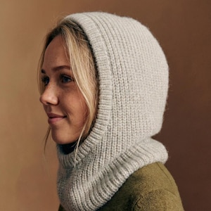 Puede incluir: Una balaclava de punto gris claro con textura acanalada. La capucha cubre la cabeza y el cuello, brindando calidez y protección. La balaclava está hecha de un material suave y acogedor, ideal para el clima frío.