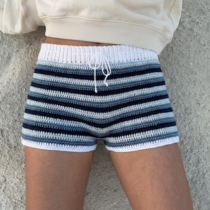 Könnte beinhalten: Gehäkelte Shorts mit horizontalen Streifen in Blau-, Weiß- und Marine-Tönen. Die Shorts haben einen weißen Kordelzug und Besatz. Das Kleidungsstück ist handgefertigt und für den Sommer geeignet.