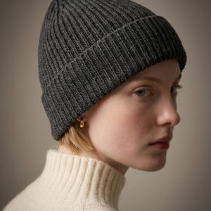 Könnte beinhalten: Ein Set aus drei Keramikbechern mit gesprenkelter, matter Oberfläche. Die Becher sind in den Farbtönen Creme, Hellgrau und Dunkelgrau gehalten. Jeder Becher hat ein schlichtes, minimalistisches Design, ideal für Kaffee oder Tee.