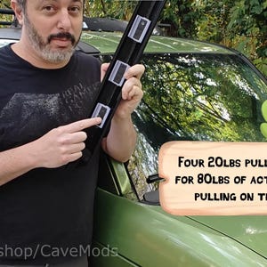 May include: A black tool with four rectangular magnets, each rated at 20 lbs of pull force, for a total of 80 lbs. The tool is being demonstrated on a green vehicle. Text on the image reads: "Four 20LBS pull magnets for 80LBS of active force pulling on the trim."