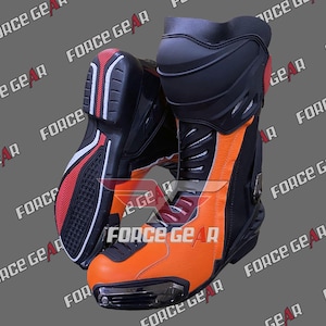 Puede incluir: Par de botas de moto negras y naranjas con el texto "FORCE GEAR". Las botas tienen un diseño elegante con zonas reforzadas, una suela negra con detalles en rojo y blanco y una puntera protectora. Las botas están diseñadas para la seguridad y el rendimiento.