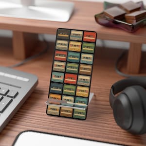 Może przedstawiać: Czarny stojak na telefon z kolorowym wzorem kaset retro. Stojak wykonany jest z wytrzymałego materiału i ma elegancki design. Kasety są w różnych kolorach, w tym czerwonym, zielonym i żółtym.