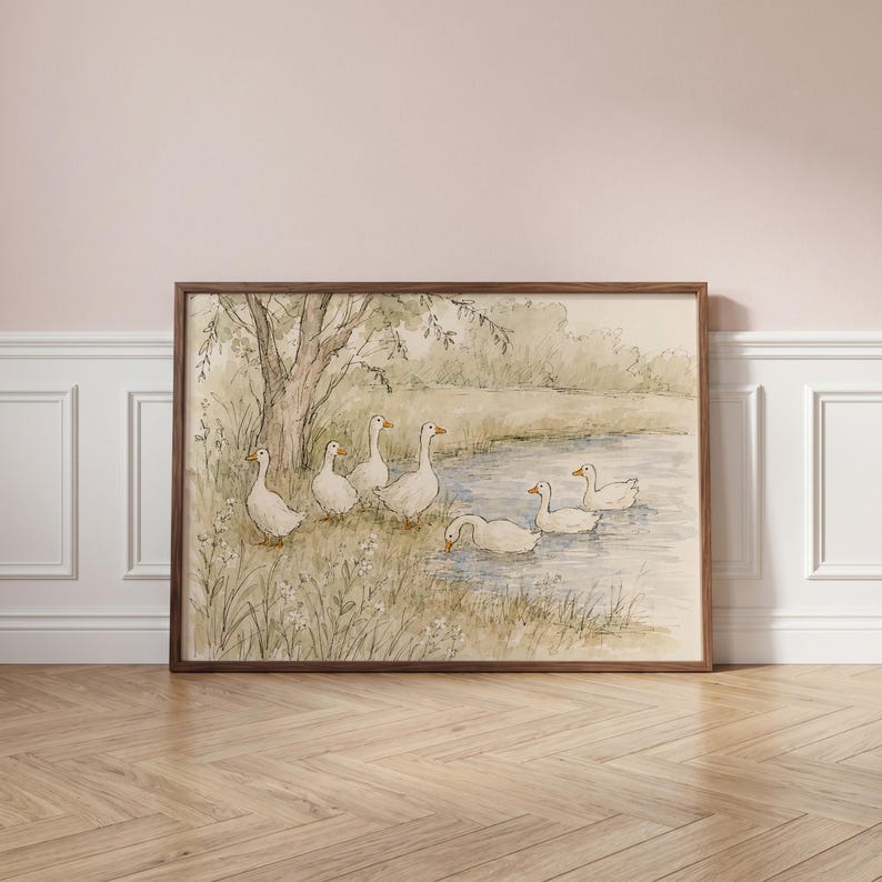 May include: A framed watercolor print depicting a group of white geese near a pond. Three geese stand on the grassy bank near a tree, while three others swim in the water. The scene is rendered in soft, muted earth tones and light green hues.