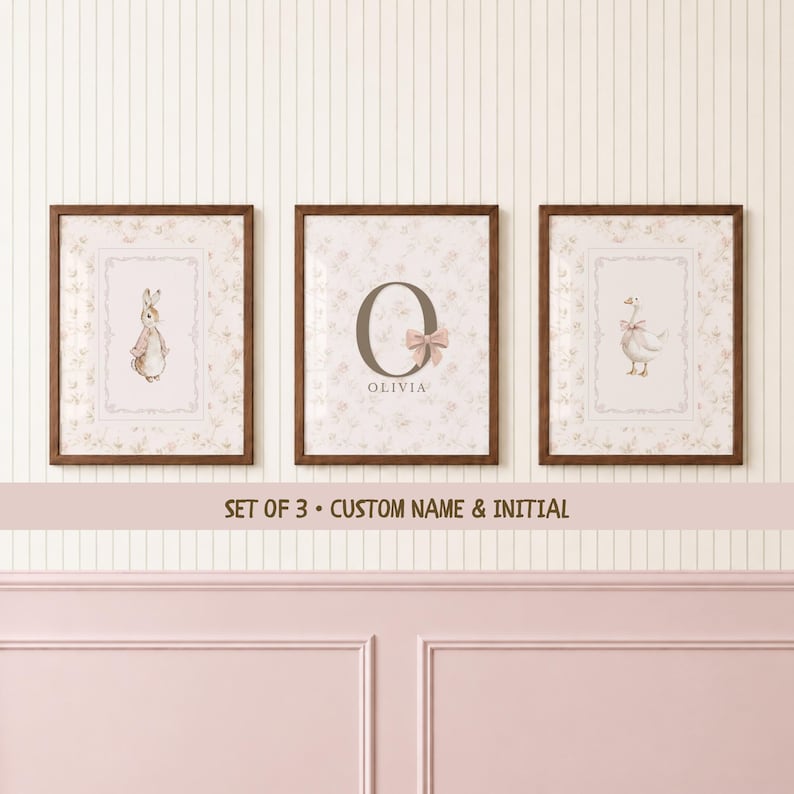May include: A set of three framed wall art prints featuring a light floral background. The left print shows a rabbit, the center print displays the letter O with a pink bow and the name OLIVIA, and the right print depicts a goose. SET OF 3 &bull; CUSTOM NAME & INITIAL.