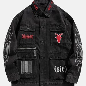 May include: Black denim jacket with multiple pockets, a zipper, and button closures. Features red embroidered text on the collar and chest, along with a red goat head patch and white tribal designs on the sleeves. The word "Slipknot" is also embroidered.