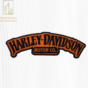 May include: Embroidered Harley-Davidson patch in orange and black. The arched text reads "HARLEY-DAVIDSON" above "MOTOR CO." in a rectangular box. The patch has a black border and is set against a white background.