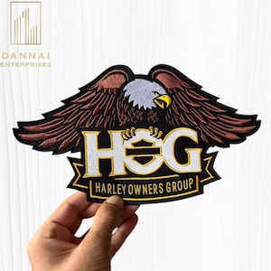 May include: Embroidered patch featuring a detailed eagle with outstretched wings, clutching the letters "HOG" in white and gold. The text "HARLEY OWNERS GROUP" is below. The patch is black, brown, white, and gold.