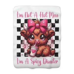 Könnte beinhalten: Weiße Decke mit einer Cartoon-Illustration einer Highland-Kuh mit rosa Schleife, die aus einer Tasse mit Herz trinkt. Der Text lautet: "I'm Not A Hot Mess, I'm A Spicy Disaster."