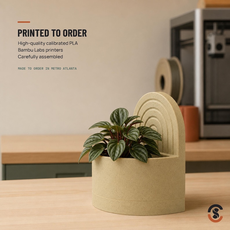 A light beige bookend planter with a small green plant, with text overlay "PRINTED TO ORDER High-quality calibrated PLA Bambu Labs printers Carefully assembled MADE TO ORDER IN METRO ATLANTA."