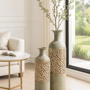 Peut inclure: Deux grands vases décoratifs vert sauge avec un motif tissé naturel. L'un des vases est plus grand que l'autre. Une branche avec des bourgeons verts est dans le vase le plus grand. Les vases sont dans une pièce bien éclairée avec une fenêtre.