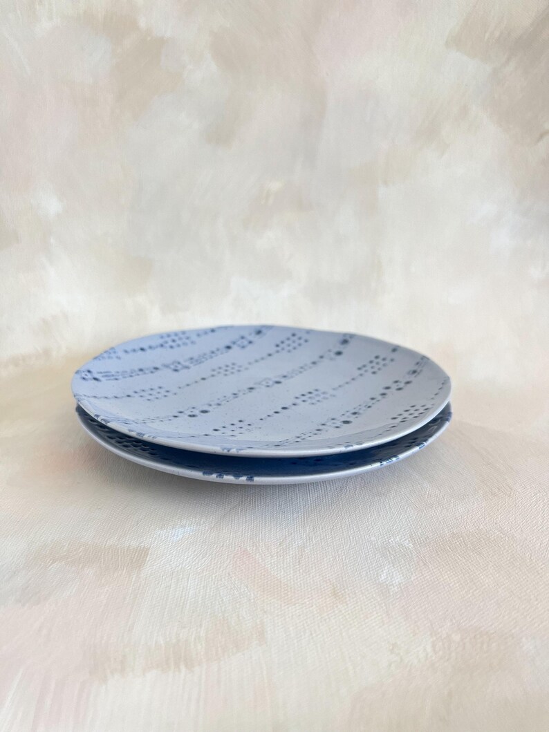 Puede incluir: Dos platos de cer&aacute;mica azul claro apilados. Los platos tienen un patr&oacute;n de puntos en un color azul m&aacute;s oscuro. Los platos son redondos y tienen un dise&ntilde;o simple y elegante.