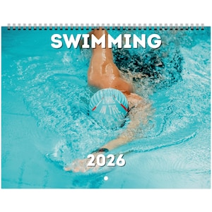 Puede incluir: Calendario encuadernado en espiral con la palabra "SWIMMING" en letras blancas grandes en la parte superior. La imagen muestra a una persona nadando en una piscina, con el año "2026" en la parte inferior. El nadador lleva un gorro azul.