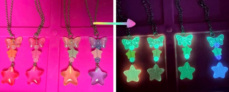 May include: Three necklaces with butterfly and star pendants. The pendants have a gradient of colors, including pink, orange, and purple. The necklaces glow in the dark, with the butterfly and stars emitting a bright green light.