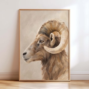 May include: A framed wall art print featuring a side profile painting of a bighorn sheep with large, curved tan horns. The animal is rendered in textured brushstrokes with shades of brown, beige, and cream against a neutral, light-coloured background.