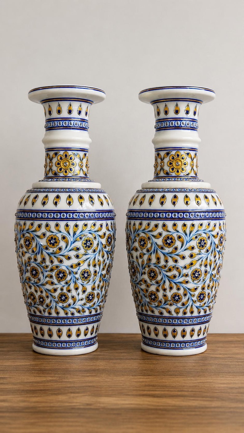 K&ouml;nnte beinhalten: Ein Paar passende wei&szlig;e Keramikvasen mit aufwendigen, handbemalten Blumenmustern in Blau- und Goldt&ouml;nen. Das Design umfasst sich wiederholende Bl&uuml;tenblattmotive, geschwungene Ranken und kleine kreisf&ouml;rmige Akzente am Hals und Fu&szlig;.