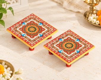 May include: Two square wooden platforms with four small red feet each. The tops feature a vibrant, symmetrical floral pattern in shades of red, orange, green, and blue, accented with white dots and intricate gold-toned decorative borders.
