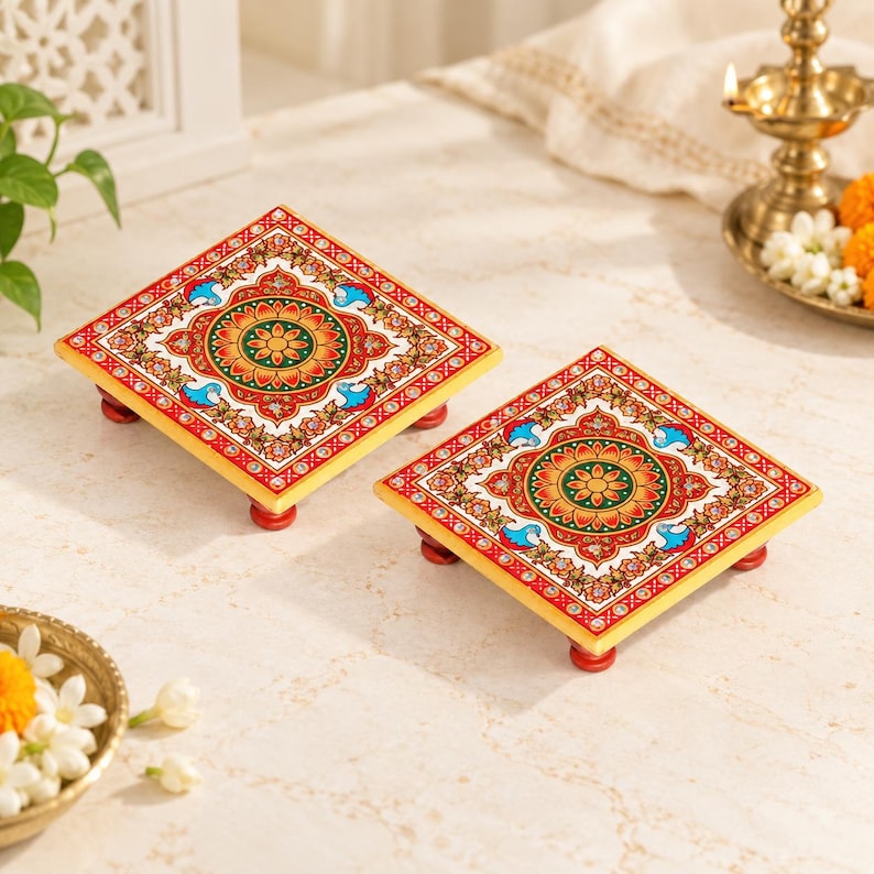 May include: Two square wooden platforms with four small red feet each. The tops feature a vibrant, symmetrical floral pattern in shades of red, orange, green, and blue, accented with white dots and intricate gold-toned decorative borders.
